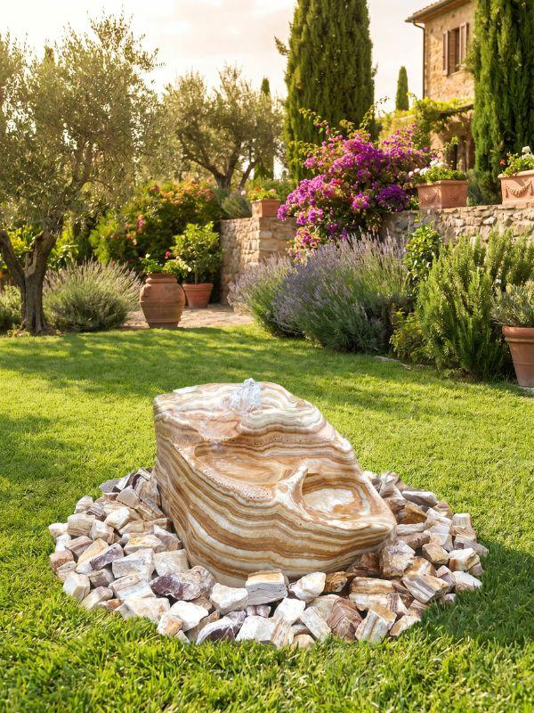 Fontaine de jardin en pierre naturelle, marbre clair veiné, dans un jardin méditerranéen